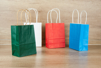 Colorful paper shopping bags on the floor against a wooden wall background