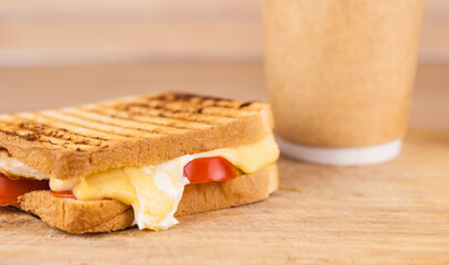 big sandwich with ham, cheese, tomatoes and disposable coffee cup on toasted bread