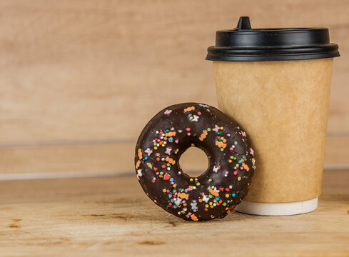 A chocolate donut or doughnut with hot cup of fresh coffee or tea.