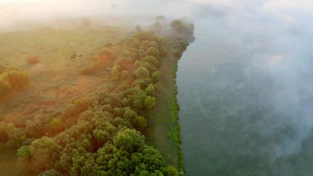 4k drone flying over foggy river footage (Ultra High Definition). Picturesque summer sunrise in countryside. Camp side on the shore of Seret river, Ukraine, Europe..