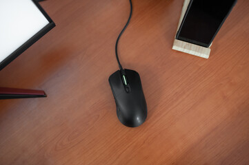 Black gaming mouse with keyboard and mobile phone on wooden stand on wooden table