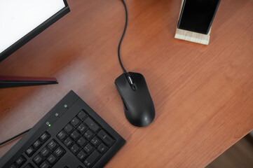 Black gaming mouse with keyboard and mobile phone on wooden stand on wooden table