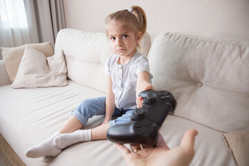 Mother taking away joystick  from her daughter. Problem of video games and gadgets addiction.