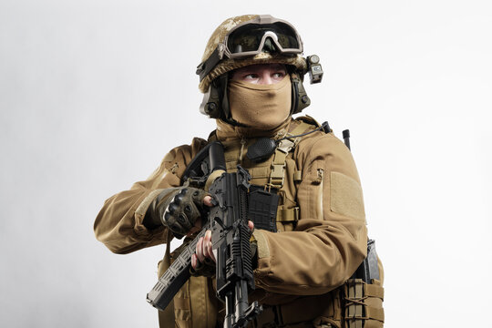 Male soldier in tactical equipment and uniform (coyote brown color) . Shot in studio on a white background