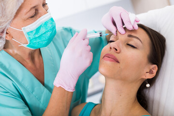 Female client receiving cosmetic injection from professional cosmetician