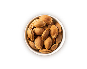 Studio shot of apricot pits on white background. Heap of apricot pit in nutshell isolated on white. Nuts in a bowl with copy space for text. Almonds close-up. Top view.