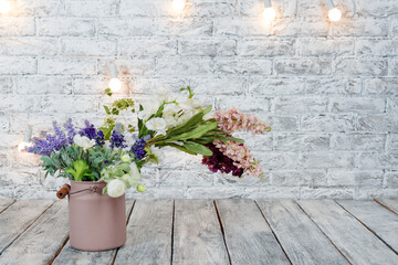 Fototapeta na wymiar Flowers with light bulbs on white brick background with wooden floor.
