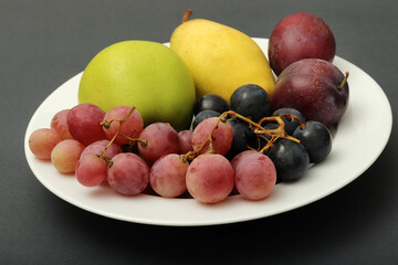 fresh fruits grape, plum, apple, pear in the plate