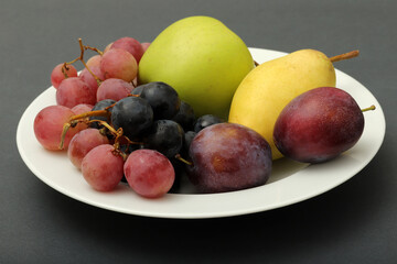 fresh fruits grape, plum, apple, pear in the plate
