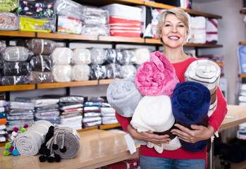 happy american aged woman enjoying purchased home textiles in textile shop