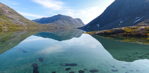Ein norwegischer Gebirgssee mit klarer Spiegelung der Berge an einem sonnigen Tag