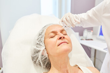 Obraz na płótnie Canvas Doctor injects hyaluronic acid dermal filler during a facelift