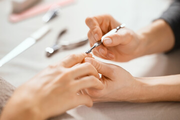 Beautician using cuticle pusher on woman hand