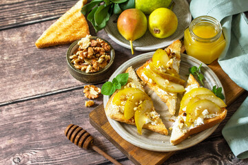Summer healthy breakfast or snack, antipasto. Grill toast with caramelized pear, honey, nuts and cheese ricotta on a wooden rustic table. Copy space.