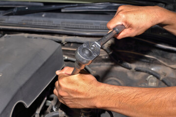The mechanic is using a wrench to maintain the engine