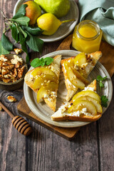 Summer healthy breakfast or snack, antipasto. Grill toast with caramelized pear, honey, nuts and cheese ricotta on a wooden rustic table. Copy space.
