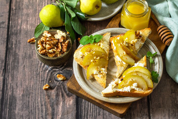 Summer healthy breakfast or snack, antipasto. Grill toast with caramelized pear, honey, nuts and cheese ricotta on a wooden rustic table. Copy space.