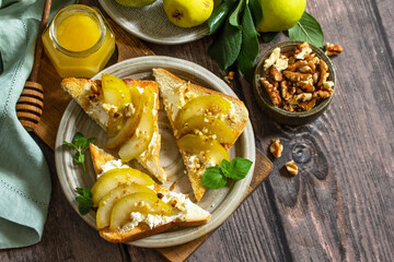 Summer healthy breakfast or snack, antipasto. Grill toast with caramelized pear, honey, nuts and cheese ricotta on a wooden rustic table. Top view flat lay. Copy space.