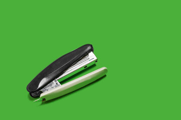 black stapler isolated on a green background