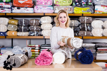 happy russian female shop assistant demonstrating assortment of home textiles