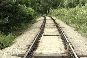 Fototapeta premium turn of the railway. Steel rails on concrete sleepers disappear from view, going deep into the forest thicket