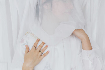 Sensual beautiful woman posing under soft white fabric, modern veil. Mental health. Bridal morning