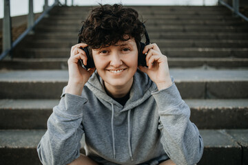 Junger Mensch sitzt auf  Stufen und hört Musik mit Kopfhörern 