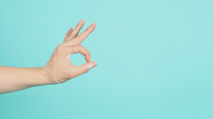 Hand is do a okay hand sign and have foam soap bubbles on a green mint or Tiffany Blue isolated background
