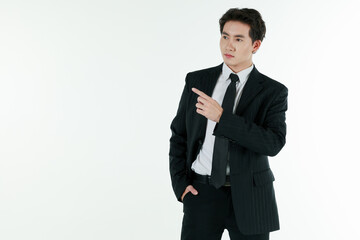 Portrait of self-confidence young and handsome Asian businessman in black suit standing in elegant pose and pointing finger, copy space studio shot isolated on white background