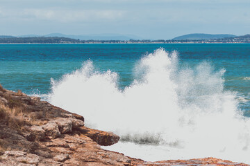 big waves crashing against rocky shoreline in Tasmania, Australia