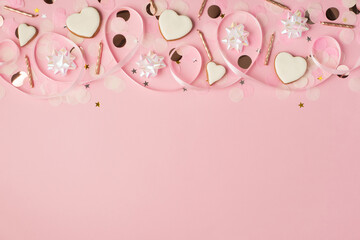 Top view photo of birthday composition with white ribbon stars golden taper candles heart-shaped cookies serpentine and confetti on isolated pastel pink background with copyspace