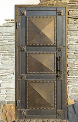 Forged door with flower decorations in brick wall.