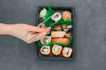 Top view of Asian sushi set with female hand holding chopsticks