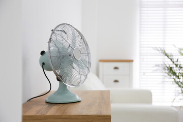 Modern electric fan on wooden table indoors. Space for text
