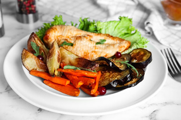 Delicious cooked chicken and vegetables on white marble table, closeup. Healthy meals from air fryer