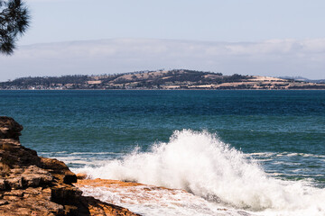 big waves crashing against rocky shoreline in Tasmania, Australia