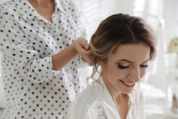 Professional stylist making wedding hairstyle for bride in salon