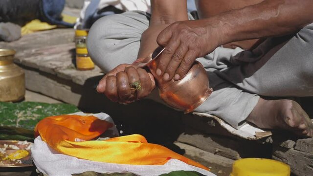 Close up of male hindu offering water to Gods from a copper vase in hindu puya.