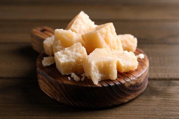 Pieces of delicious parmesan cheese on wooden table, closeup