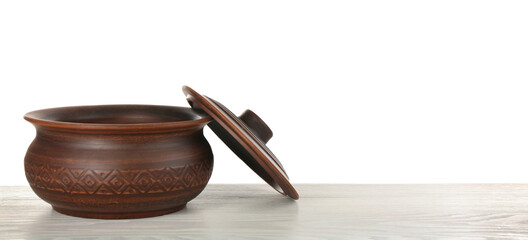 Brown clay pot on wooden table against white background. Space for text