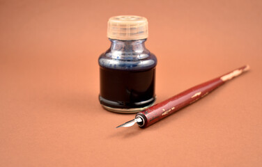 Ancient ink pen and ink-bottle frame stock images. Old inkwell with pen isolated on a brown background with copy space for text