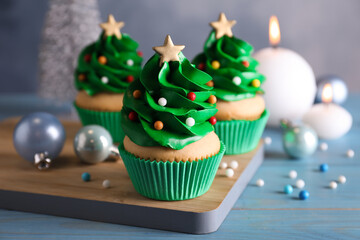 Christmas tree shaped cupcakes and decor on light blue wooden table