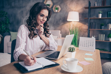 Photo of beautiful thoughtful young woman dressed striped shirt glasses looking modern device writing pen inside indoors home room