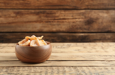 Delicious dried jackfruit slices in bowl on wooden table. Space for text