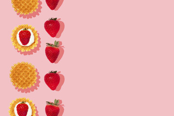 Creative pattern or frame made with strawberries and waffles on pastel pink background. Optimistic and fun breakfast or brunch concept with spring fruits. Vintage life layout.
