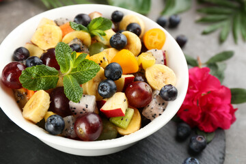 Delicious exotic fruit salad on grey table, closeup