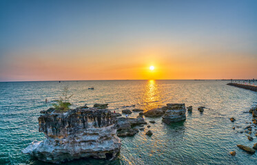 Fototapeta premium Sunset at abstract limestone beach facing the sea in pearl island Phu Quoc, Vietnam. The place remains unspoiled for ecotourism and exploration