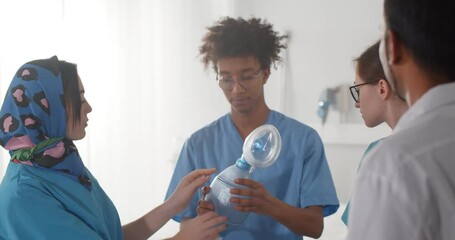 Team of diverse medical interns learning how to use breathing bag