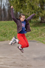 A girl with glasses rides roller skates. Seasonal outdoors children activity sport. The girl jumps with roller skates