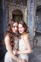 two pretty twin sister blond curly hairstyle girl in luxury house interior together, rich young people concept